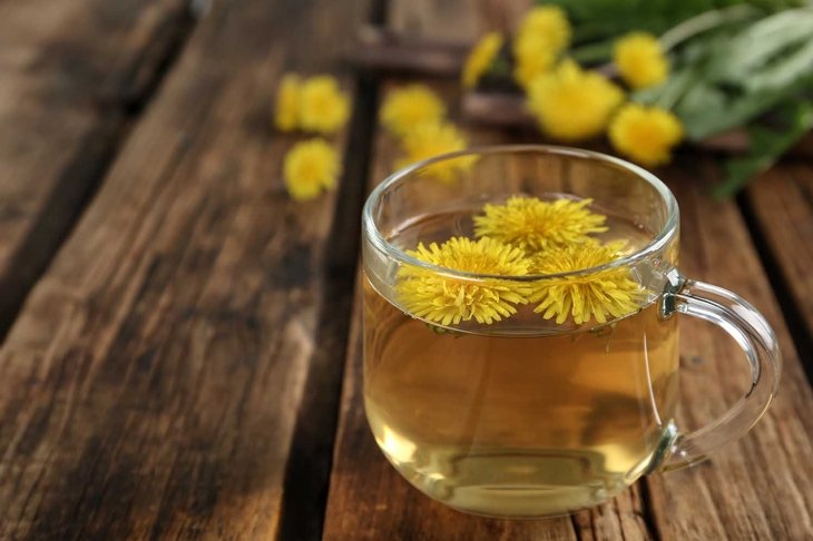 Delicious fresh dandelion tea on wooden table, closeup. Space for text