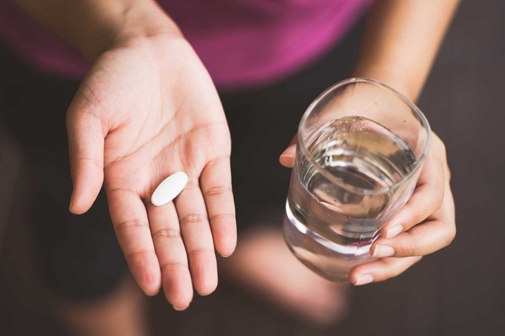 Close Up Of Girl holding Pill and glass of water.With Paracetamol.Nutritional Supplements.Sport,Diet Concept.Capsules Vitamin And Dietary Supplements.